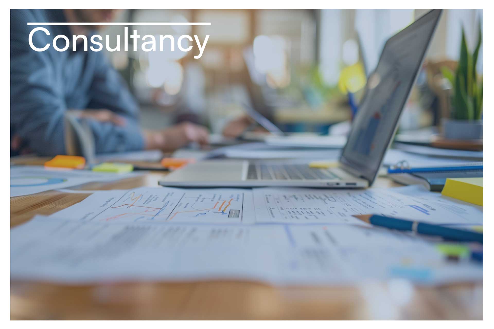 Werktafel met laptop, documenten en aantekeningen tijdens een inhoudelijke consultancy-sessie over een commercieel vraagstuk.